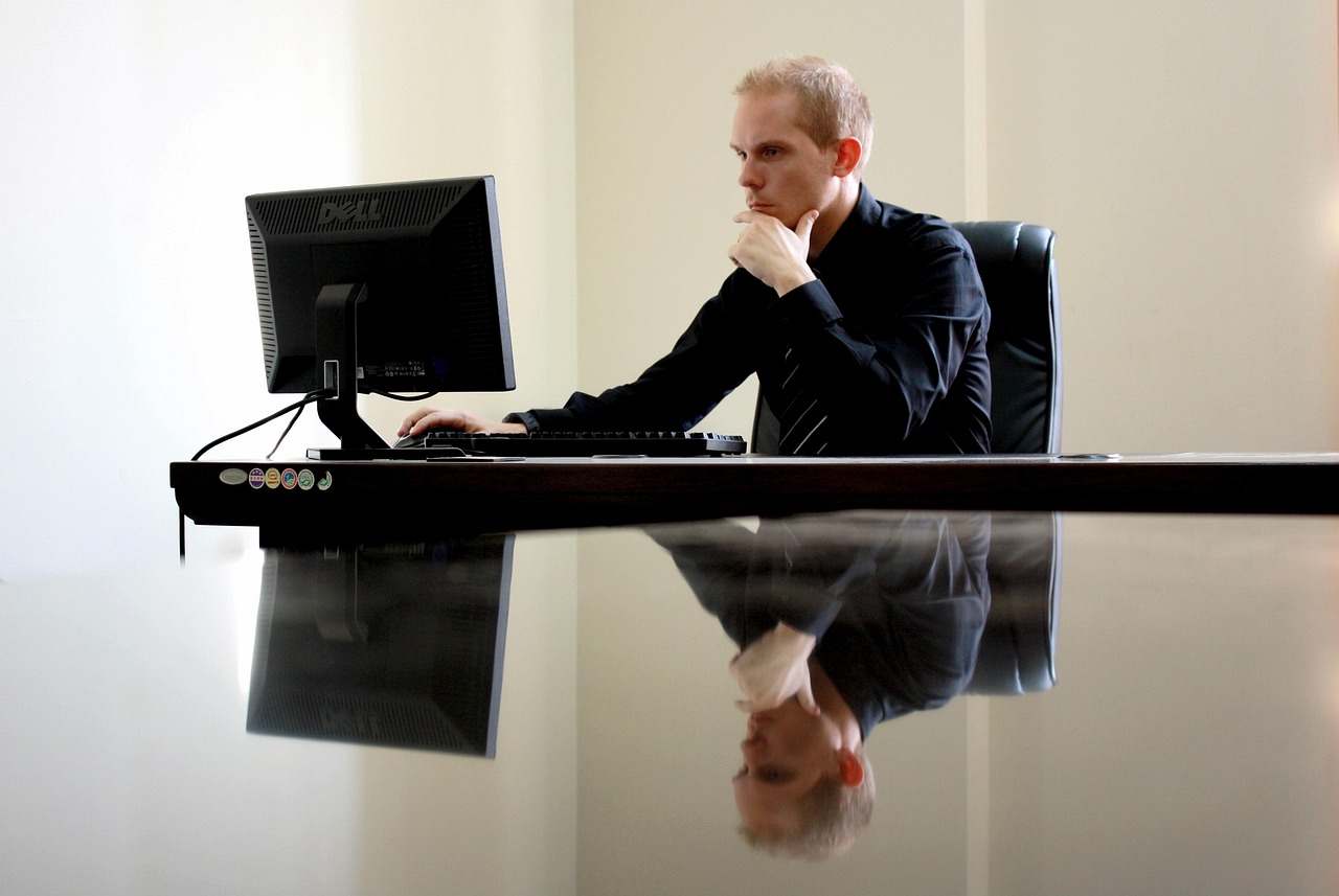 Person seated in an office chair at a desk with monitor and keyboard