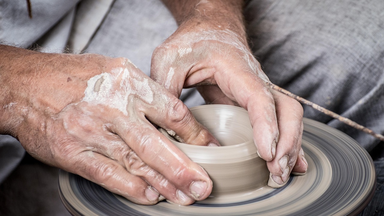 Hands shaping clay on a pottery wheel